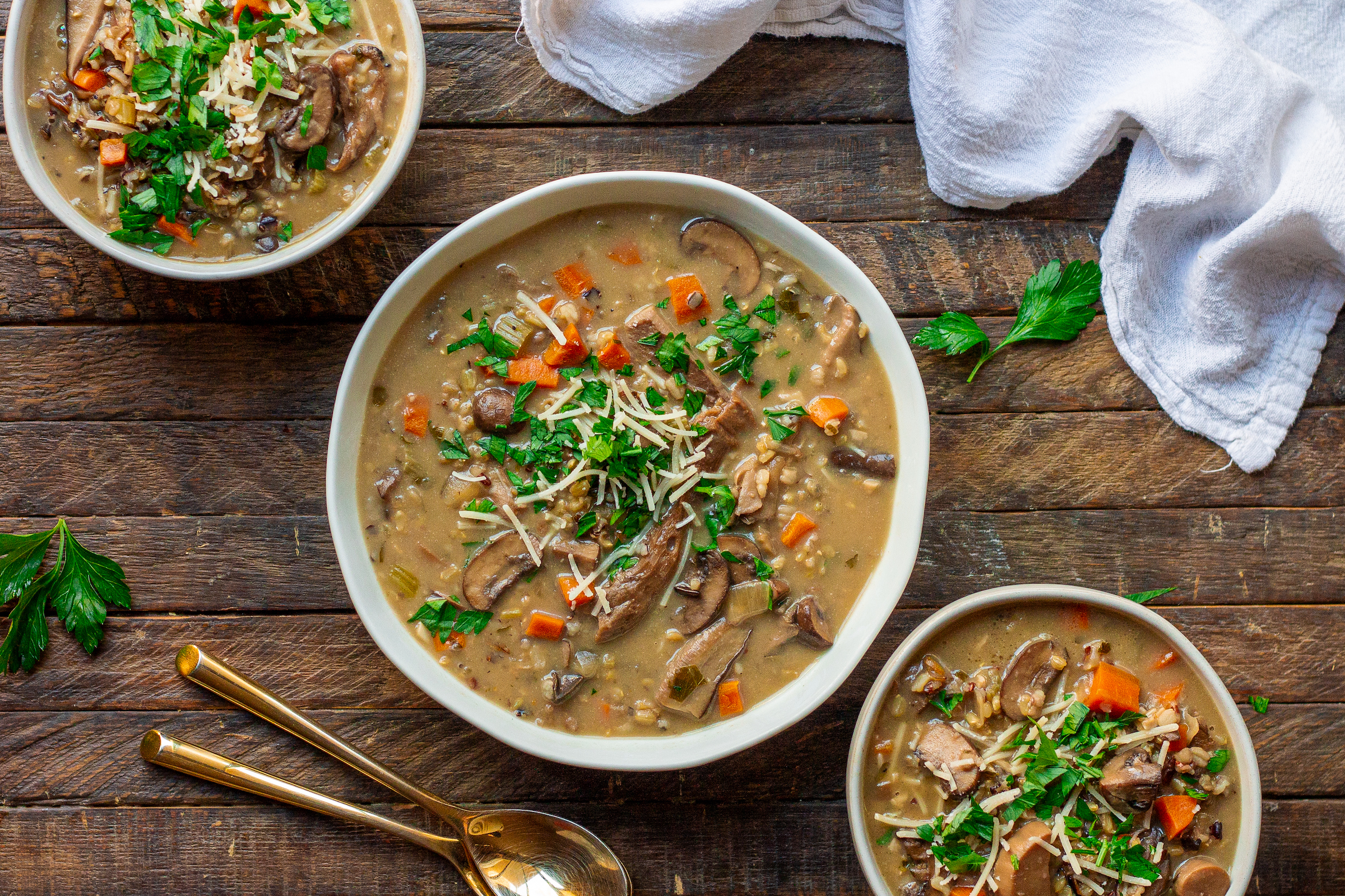 Bowl of creamy vegan wild rice and mushroom soup garnished with fresh parsley and vegan parmesan cheese.