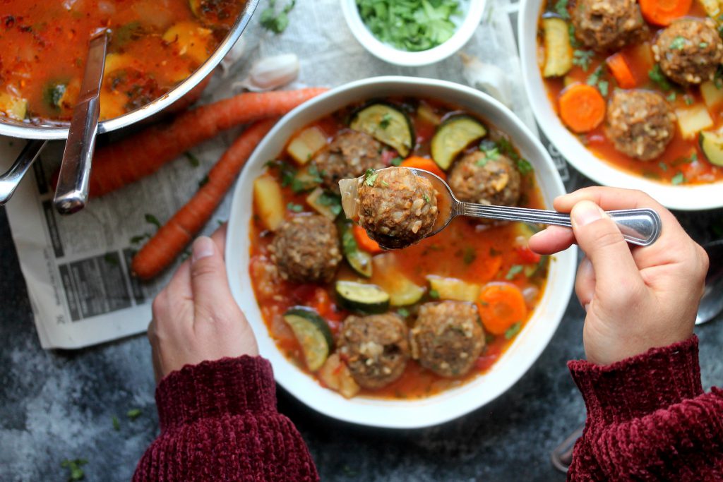 A steaming bowl of vegan Sopa de Albóndigas (Mexican Meatball Soup) with fresh cilantro and jalapeño slices.