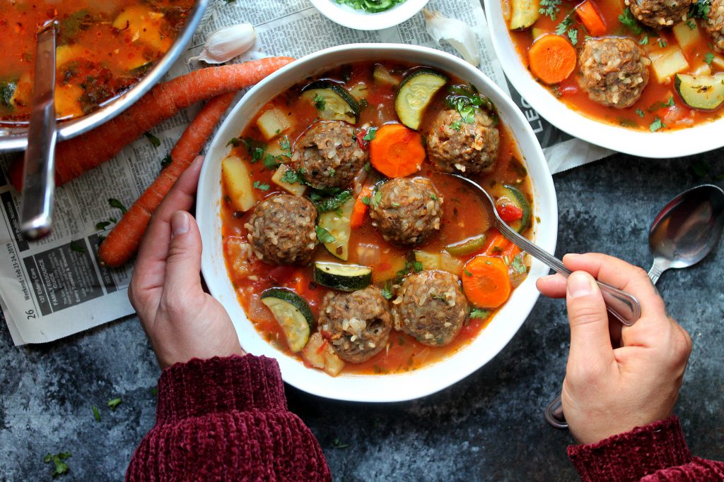 A steaming bowl of vegan Sopa de Albóndigas (Mexican Meatball Soup) with fresh cilantro and jalapeño slices.