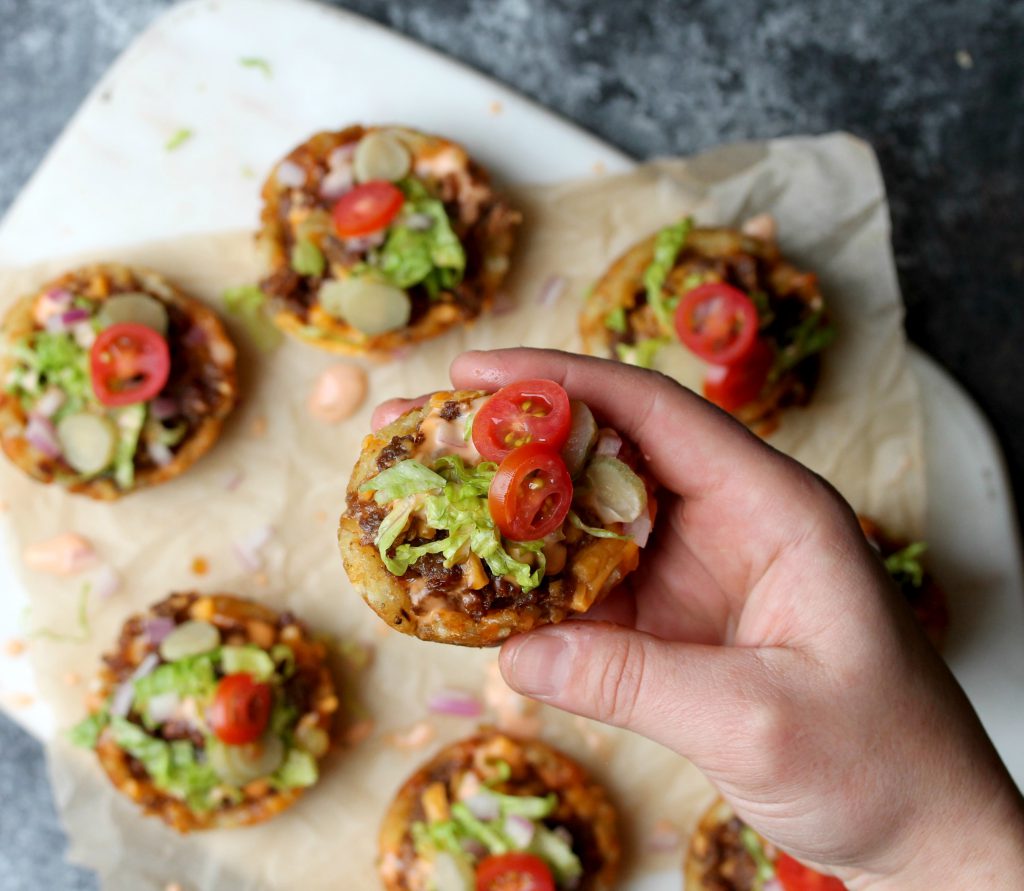 cheeseburger tater tot bites with lettuce, tomatoes, pickles, and a drizzle of burger sauce