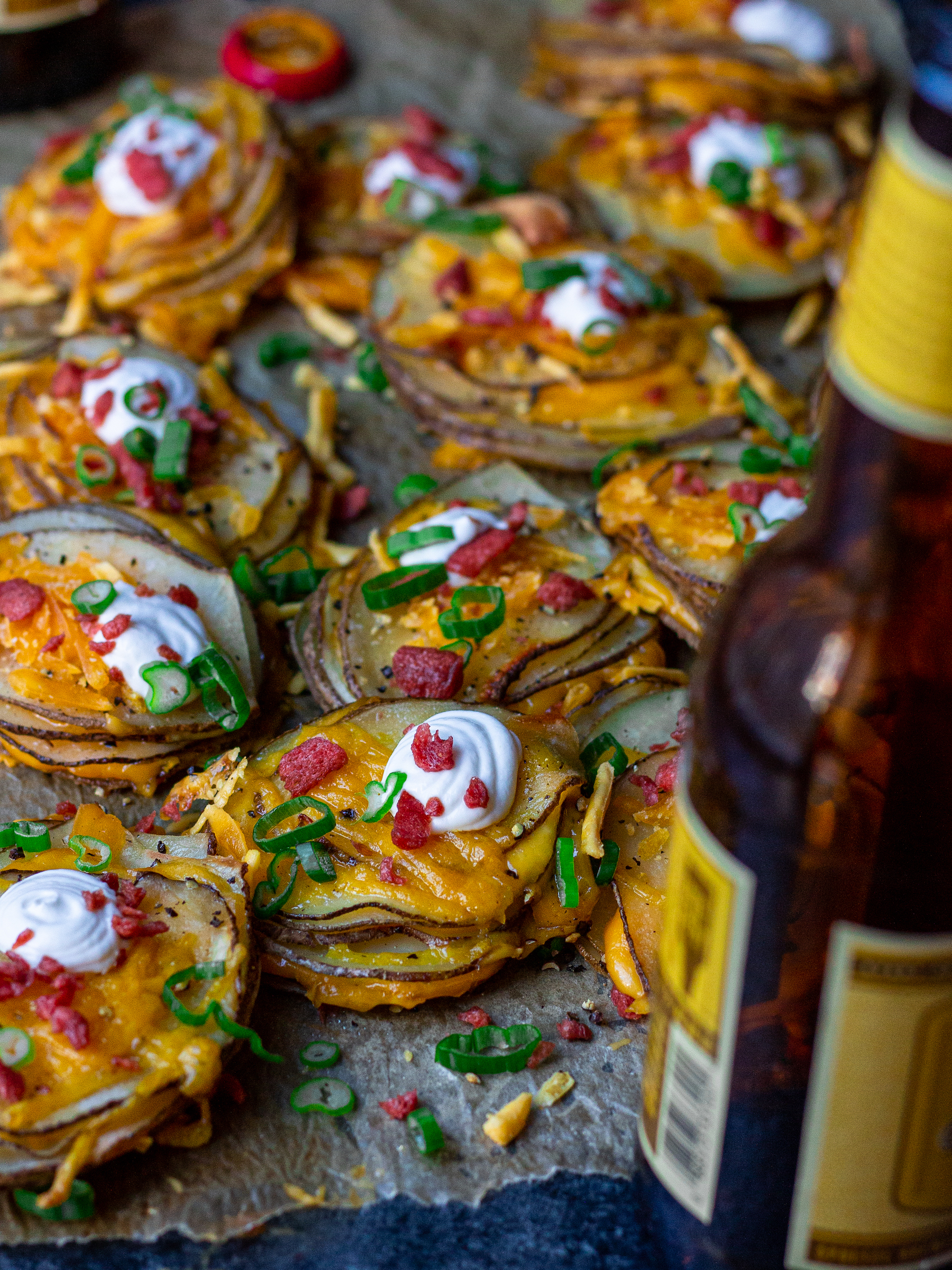 A platter of cheesy loaded potato stacks garnished with sour cream, bacon bits and chives, ready to serve.