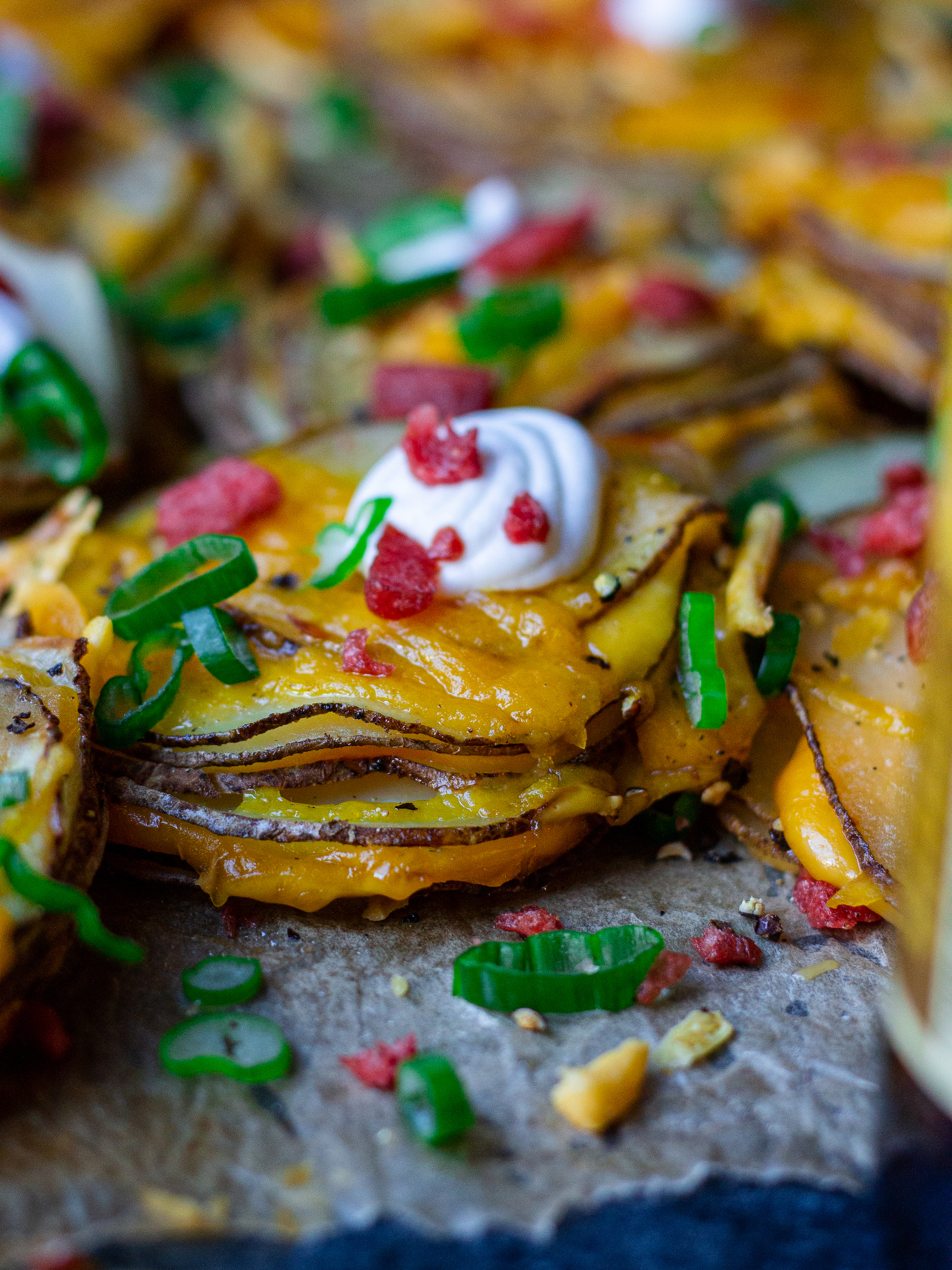A platter of cheesy loaded potato stacks garnished with sour cream, bacon bits and chives, ready to serve.
