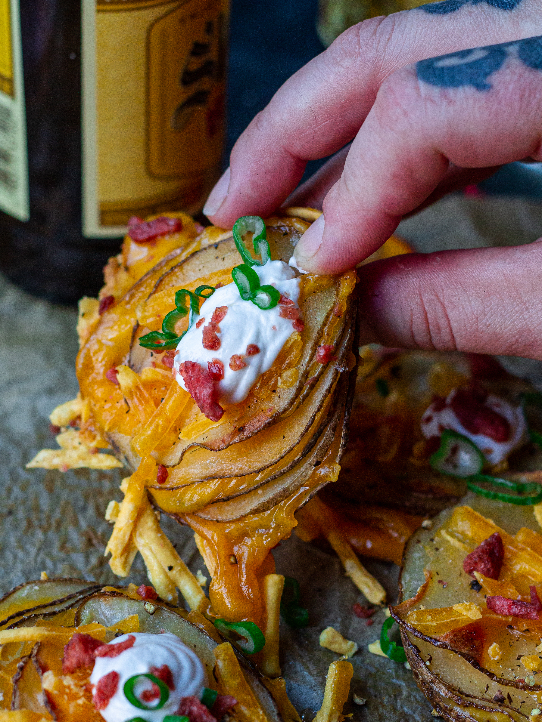 A platter of cheesy loaded potato stacks garnished with sour cream, bacon bits and chives, ready to serve.