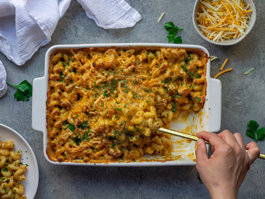 Golden-brown baked vegan mac and cheese in a casserole dish with a sprinkle of fresh parsley garnish.