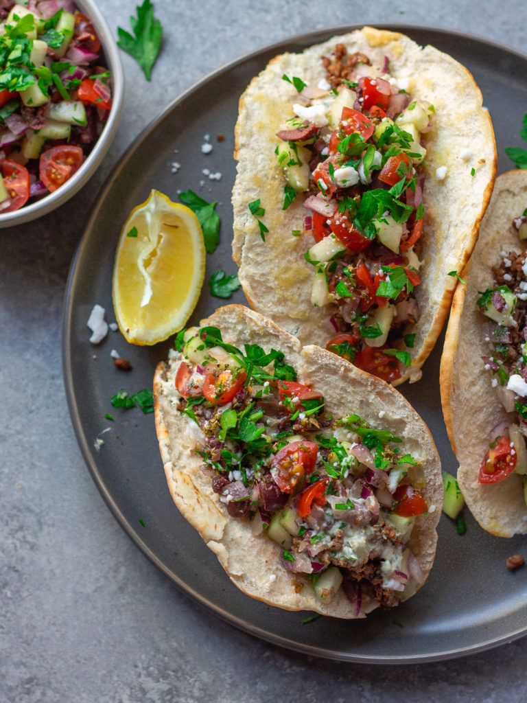 A close-up of a Vegan Mediterranean-Inspired Taco with pita bread shell, showcasing the colorful Mediterranean salad and Lightlife Smart Ground filling.