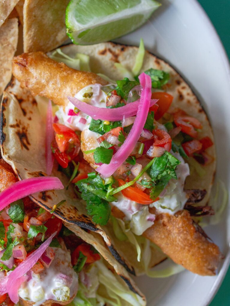 Golden crispy beer-battered vegan fish tacos topped with creamy chipotle sauce and fresh pico de Gallo.