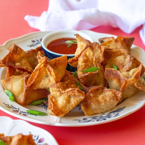Completed Vegan Crab Rangoon, garnished with chopped chives, and served with sweet chili sauce.