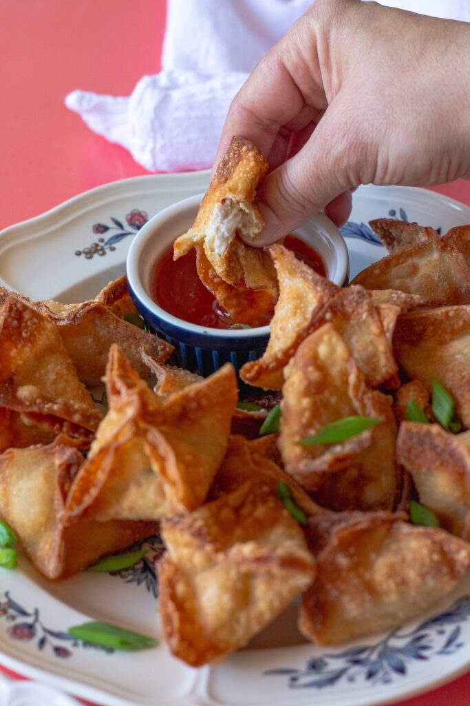 Completed Vegan Crab Rangoon, garnished with chopped chives, and served with sweet chili sauce.