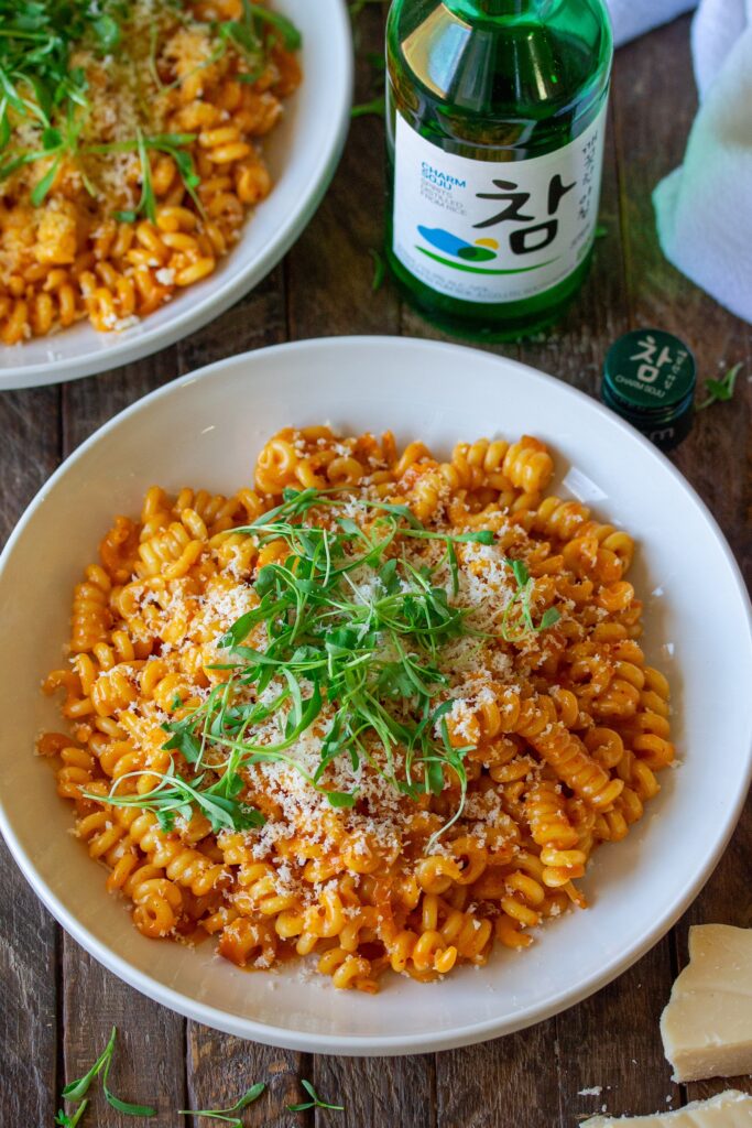 Final presentation of the Creamy Gochujang Pasta, garnished with vegan parmesan shreds and fresh cilantro micro greens 