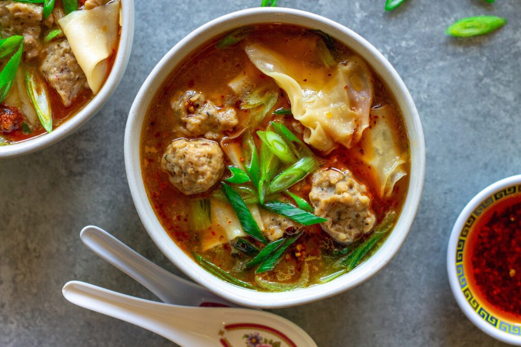 Close-up of vegan wonton meatballs floating in the flavorful broth of the deconstructed soup.