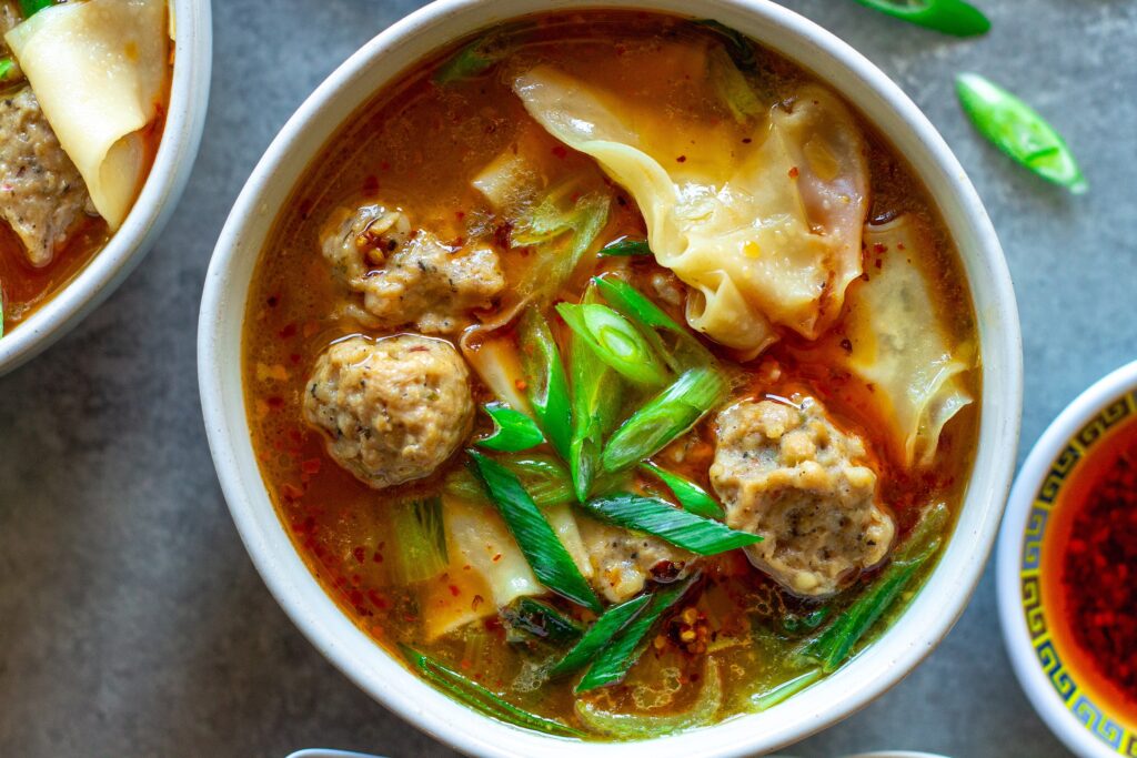 Close-up of vegan wonton meatballs floating in the flavorful broth of the deconstructed soup.