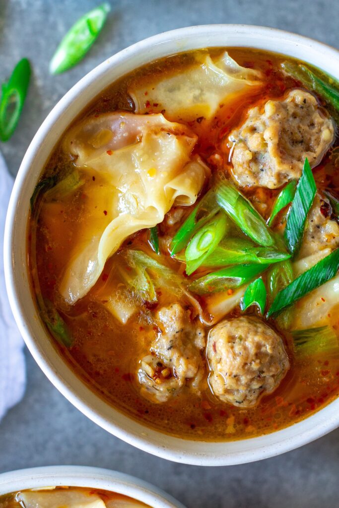 Close-up of vegan wonton meatballs floating in the flavorful broth of the deconstructed soup.