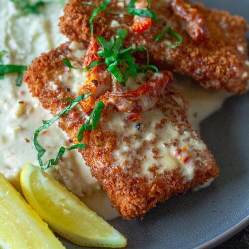 Finished dish of Parmesan-Crusted Tofu plated with lemon sauce, sundried tomatoes, and fresh basil