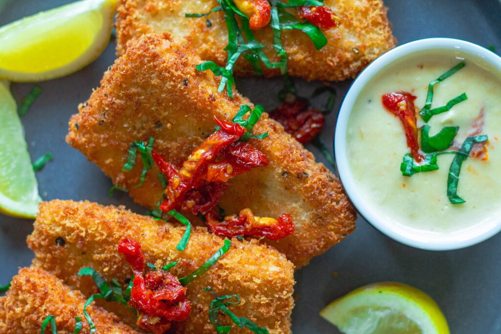 Finished dish of Parmesan-Crusted Tofu plated with lemon sauce, sundried tomatoes, and fresh basil