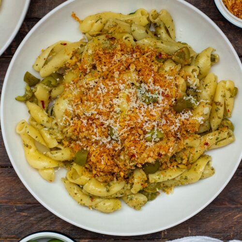 A plate of Vegan Green Olive Pasta garnished with vegan parmesan and fresh minced parsley