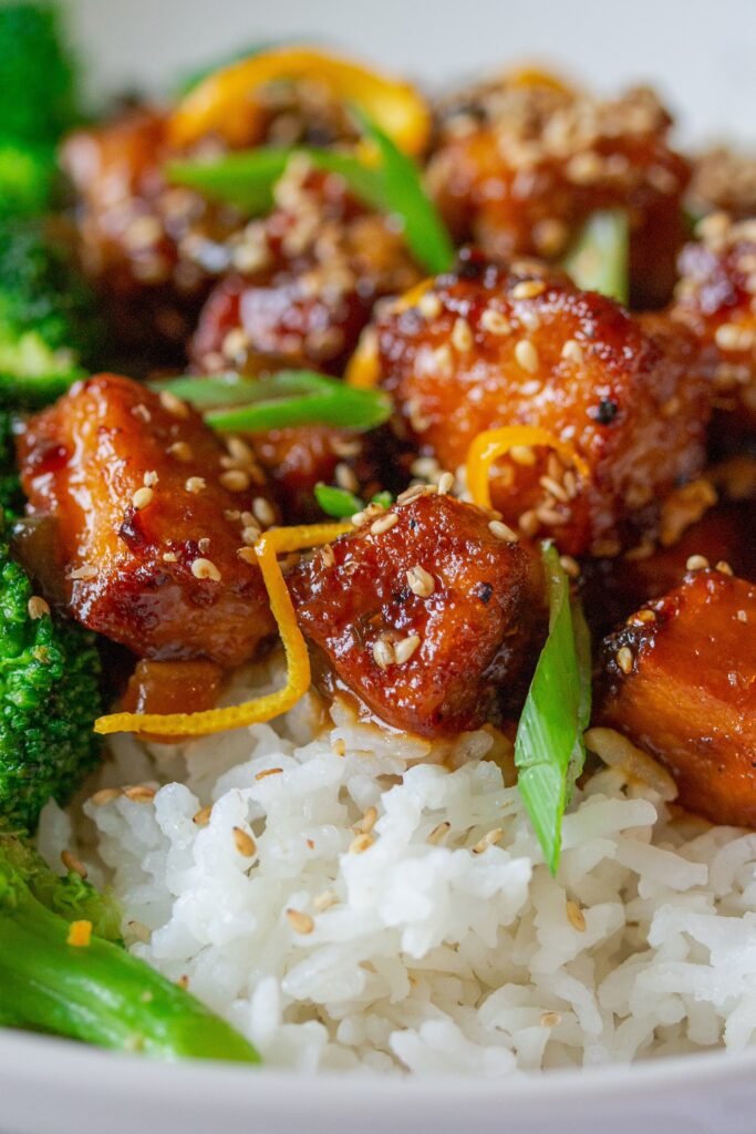 A stunning platter showcasing the finished dish – orange glazed tofu with vibrant garnishes and side dishes.