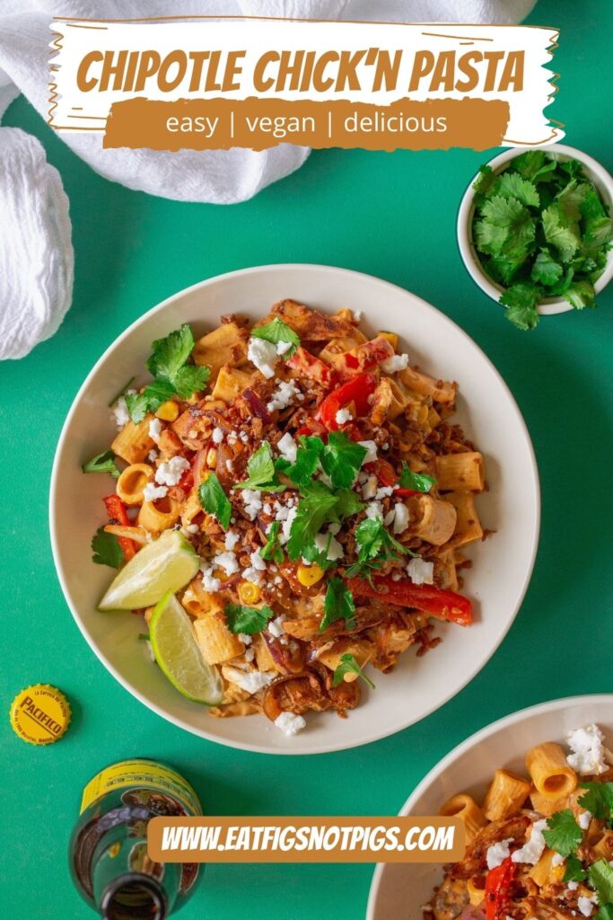 A serving plate showcasing the final dish of Vegan Chipotle Chicken Pasta, topped with vegan feta, bac'n bits, and fresh cilantro, with lime wedges on the side.