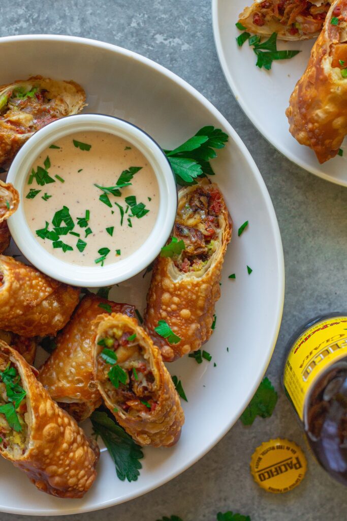 Close-up of a cut-open avocado club egg roll showcasing the flavorful filling of seasoned vegan chicken, avocado, tomatoes, and vegan cheese.