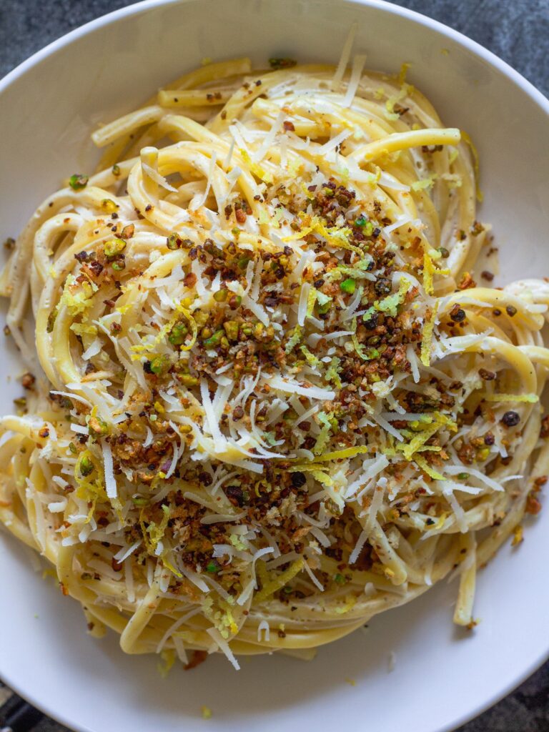 Cooked pasta coated in creamy lemon sauce with homemade garlicky pistachio breadcrumbs.