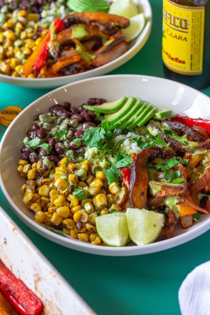 Vegan Mushroom Fajita Bowl with cilantro lime rice, roasted portobello mushrooms, black beans, corn, avocado, and drizzled with cilantro lime crema.