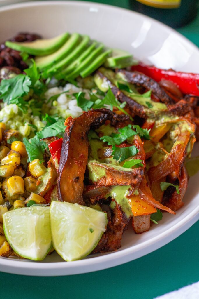 Vegan Mushroom Fajita Bowl with cilantro lime rice, roasted portobello mushrooms, black beans, corn, avocado, and drizzled with cilantro lime crema.