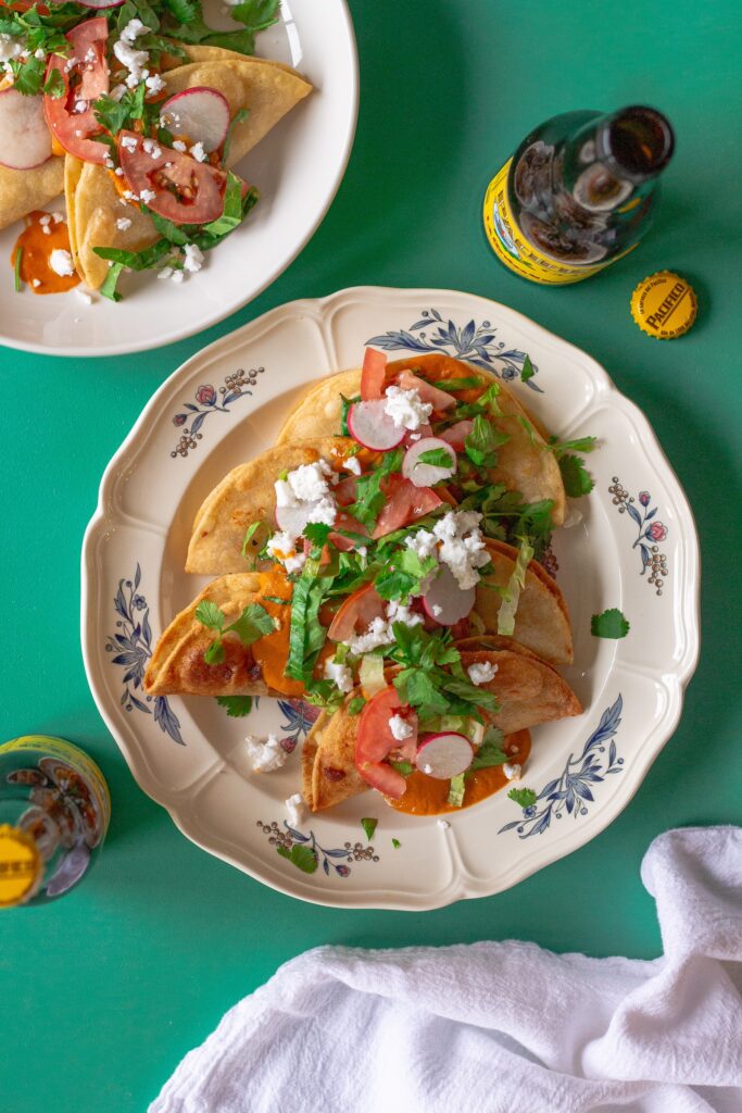 Homemade crispy potato tacos served with garlic tomato sauce and assorted garnishes