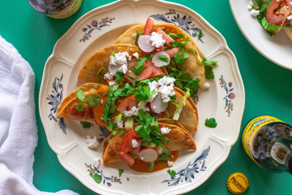 Homemade crispy potato tacos served with garlic tomato sauce and assorted garnishes