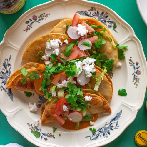 Homemade crispy potato tacos served with garlic tomato sauce and assorted garnishes