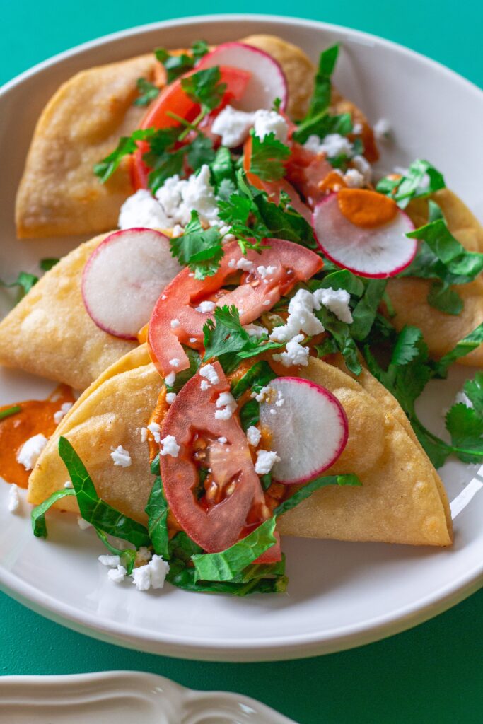 Homemade crispy potato tacos served with garlic tomato sauce and assorted garnishes