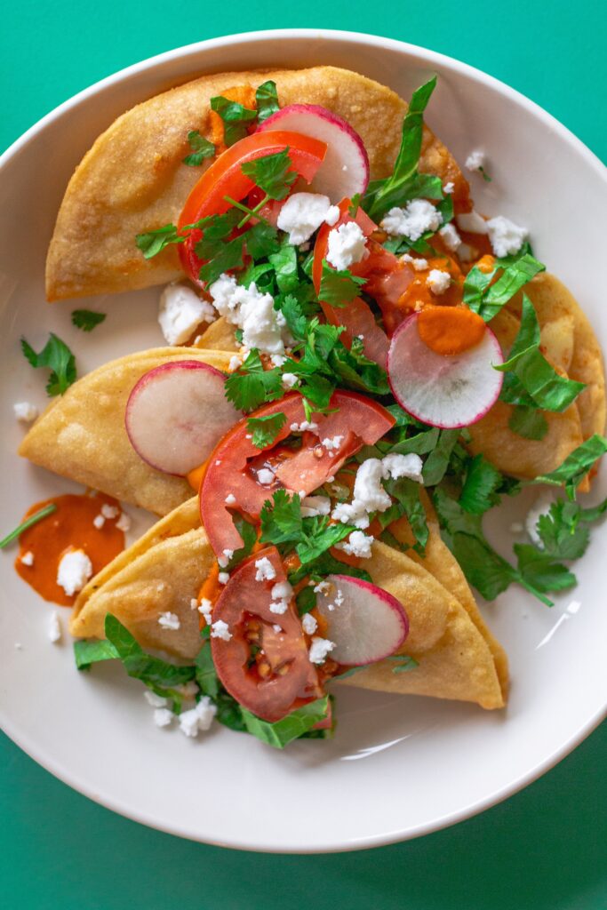 Homemade crispy potato tacos served with garlic tomato sauce and assorted garnishes