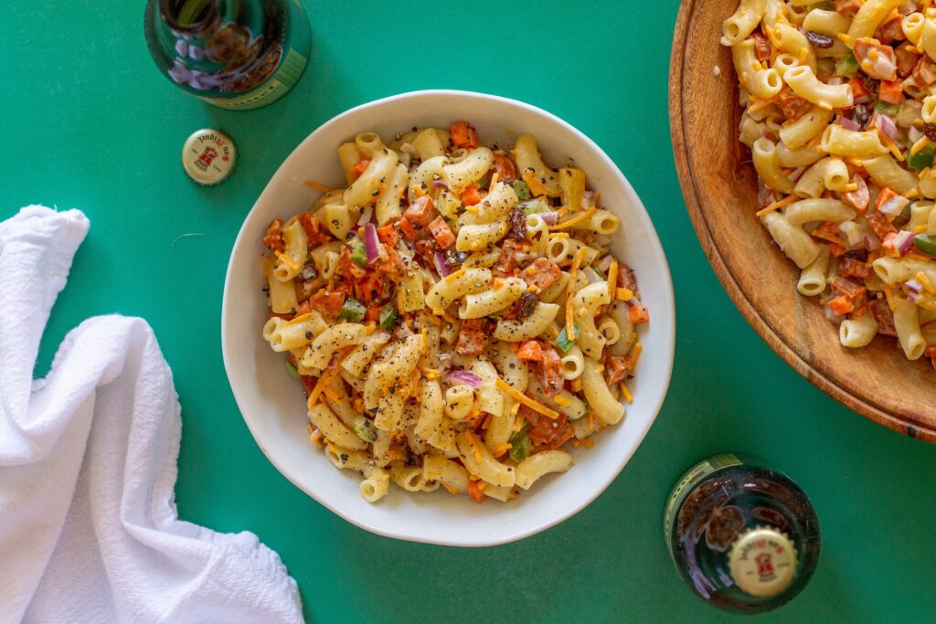 Bowl of Vegan Filipino-Style Macaroni Salad with vegetables, pineapple, and plant-based hot dogs.