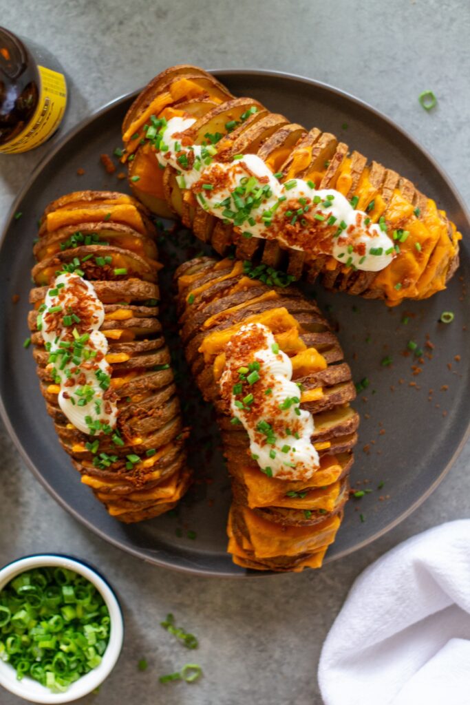 Loaded Hasselback potatoes topped with vegan sour cream, crumbled bac’n bits, and chopped green onions.