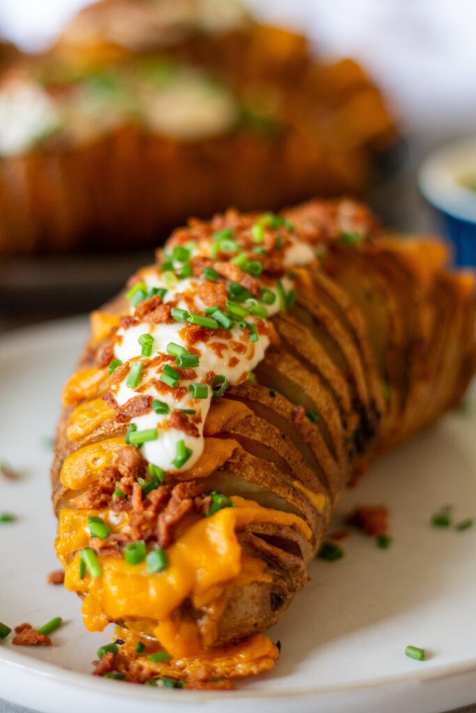 Loaded Hasselback potatoes topped with vegan sour cream, crumbled bac’n bits, and chopped green onions.