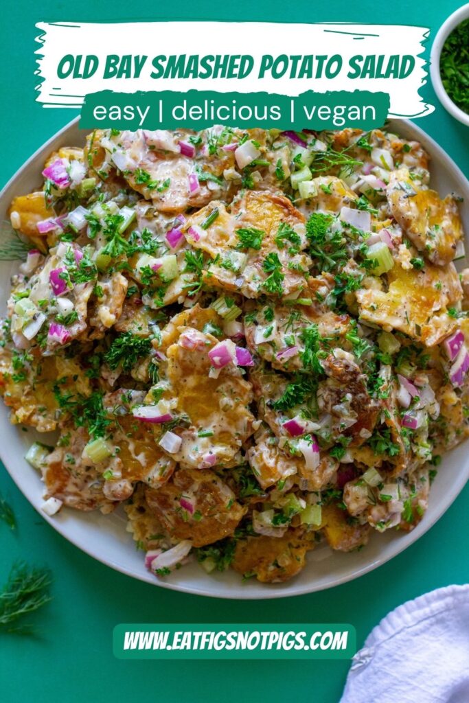A close-up of Vegan Old Bay Smashed Potato Salad in a serving bowl, showing the crispy potatoes, fresh herbs, and creamy dressing