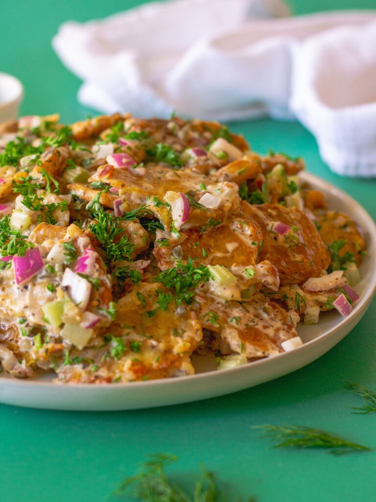 Vegan Old Bay Smashed Potato Salad served in a large bowl, garnished with fresh dill, ready to be served