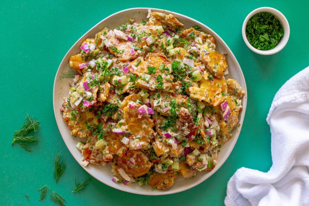 Vegan Old Bay Smashed Potato Salad served in a large bowl, garnished with fresh dill, ready to be served