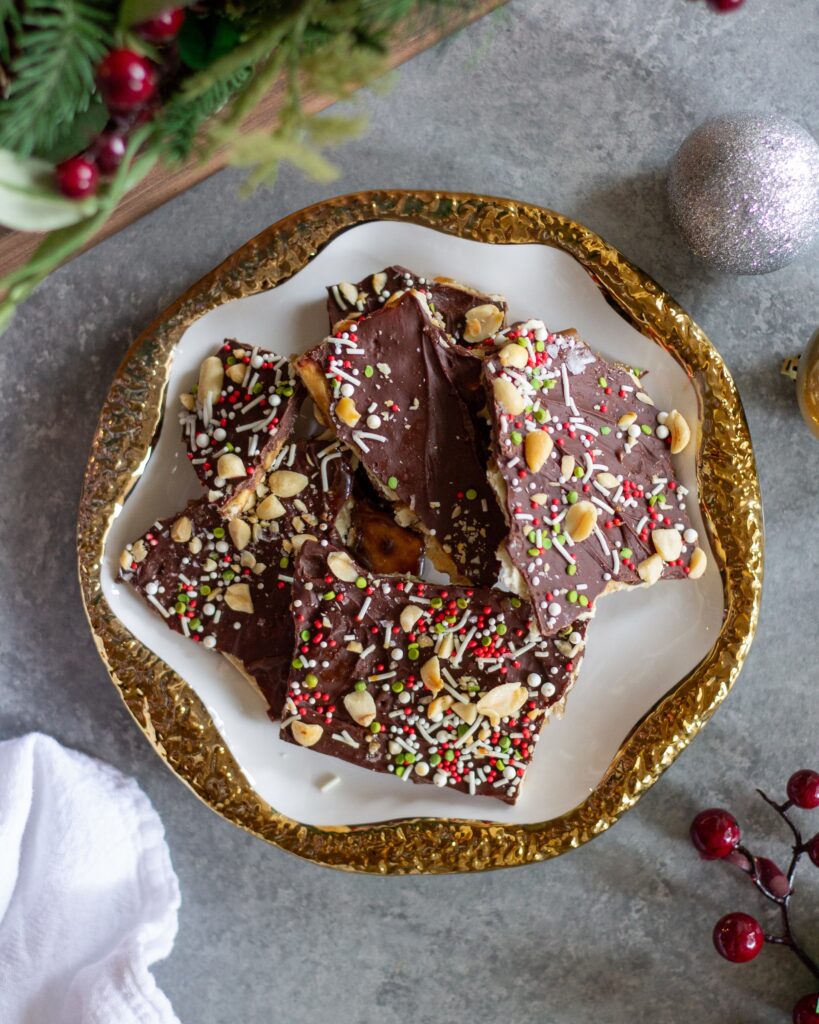 A festive plate of Christmas Cracker Toffee topped with crushed peanuts, sprinkles and sea salt, perfect for holiday celebrations.