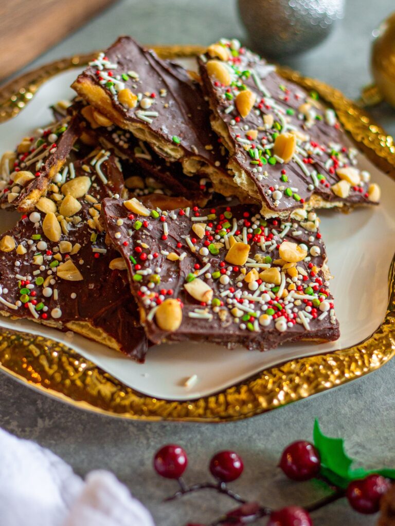 A festive plate of Christmas Cracker Toffee topped with crushed peanuts, sprinkles and sea salt, perfect for holiday celebrations.