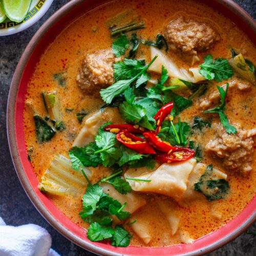 A bowl of Deconstructed Curry Wonton Soup with vibrant curry broth, wonton filling, and fresh herbs.
