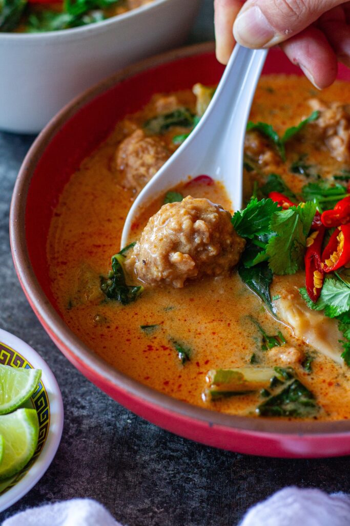 A bowl of Deconstructed Curry Wonton Soup with vibrant curry broth, wonton filling, and fresh herbs.