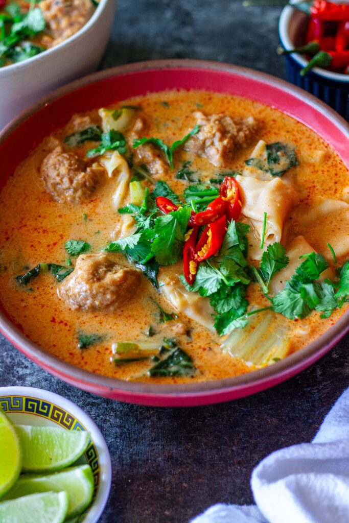 A bowl of Deconstructed Curry Wonton Soup with vibrant curry broth, wonton filling, and fresh herbs.