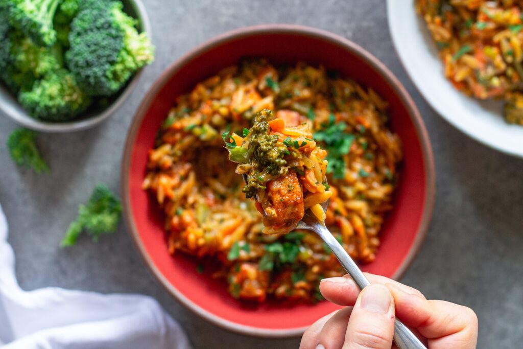 A spoonful of creamy broccoli cheddar orzo lifted from the bowl.