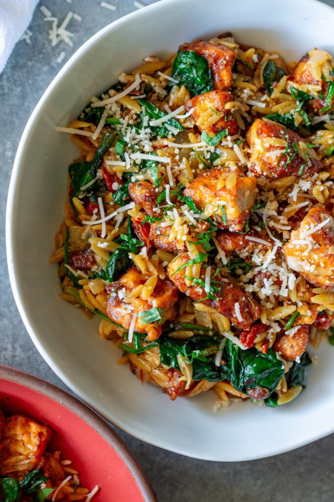 Marry Me Tofu and Orzo garnished with fresh basil and vegan parmesan.