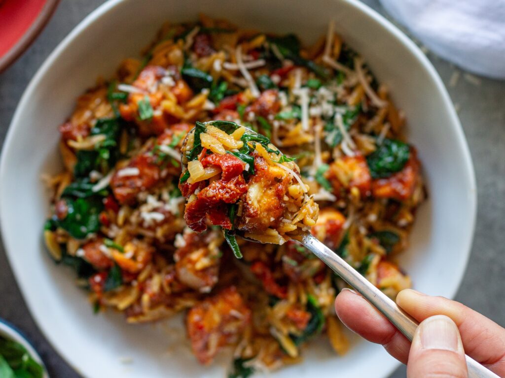 Marry Me Tofu and Orzo garnished with fresh basil and vegan parmesan.