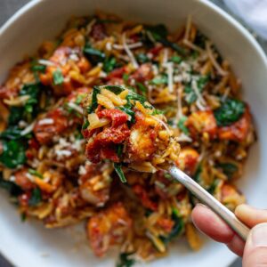 Marry Me Tofu and Orzo garnished with fresh basil and vegan parmesan.