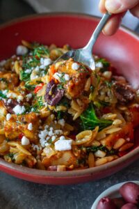 A serving of creamy orzo topped with tofu, vegan cheese, and fresh herbs.
