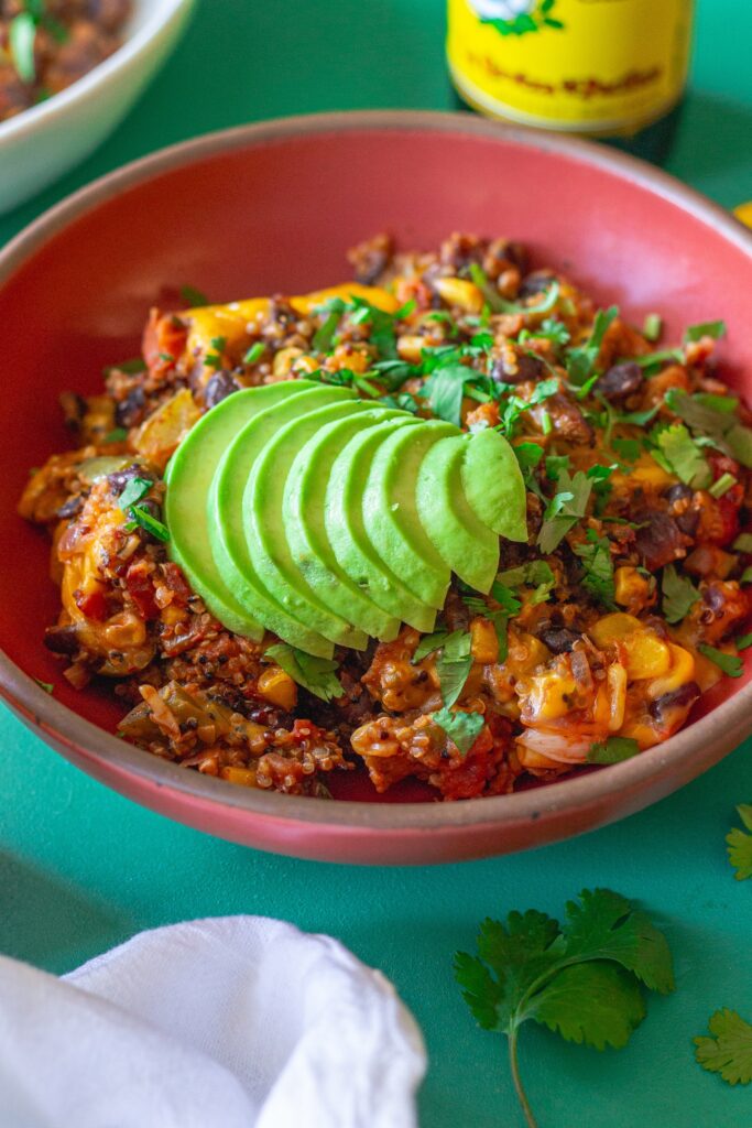 A vibrant bowl filled with Southwest Chick’n and Rice, topped with melted vegan cheese and fresh cilantro.