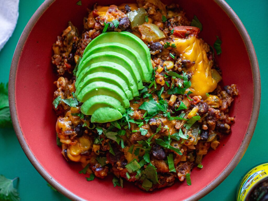 A vibrant bowl filled with Southwest Chick’n and Rice, topped with melted vegan cheese and fresh cilantro.