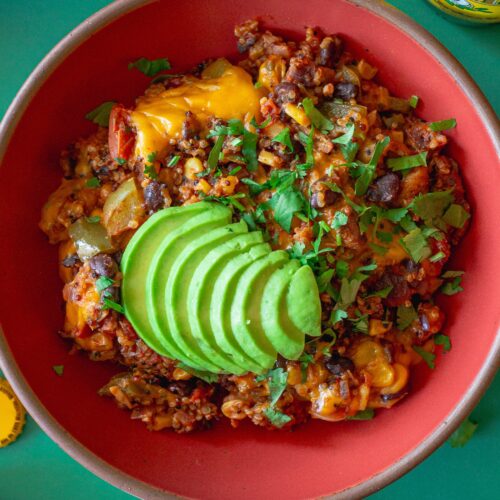 A vibrant bowl filled with Southwest Chick’n and Rice, topped with melted vegan cheese and fresh cilantro.