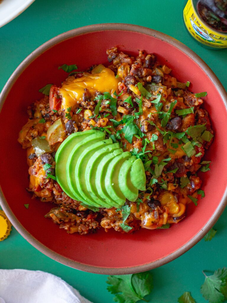 A vibrant bowl filled with Southwest Chick’n and Rice, topped with melted vegan cheese and fresh cilantro.